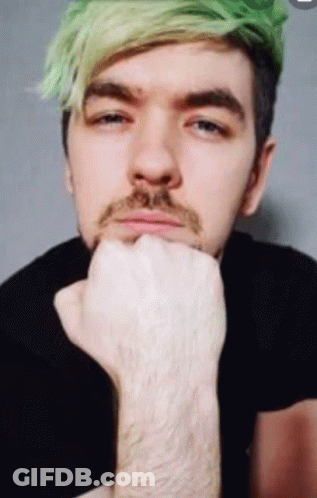 A Man With Green Hair And A Beard Holds His Hand To His Chin GIF