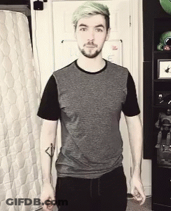 A Man With Green Hair And A Beard Is Standing In Front Of A Mattress . GIF