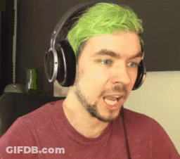 A Man With Green Hair And Headphones On Is Making A Funny Face . GIF
