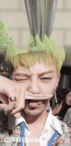 A Man With Green Hair Has A Ring On His Finger And A Tattoo On His Finger That Says Nc GIF