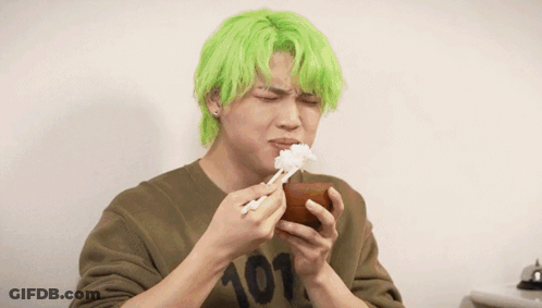 A Man With Green Hair Is Eating Rice From A Bowl Next To Another Man GIF