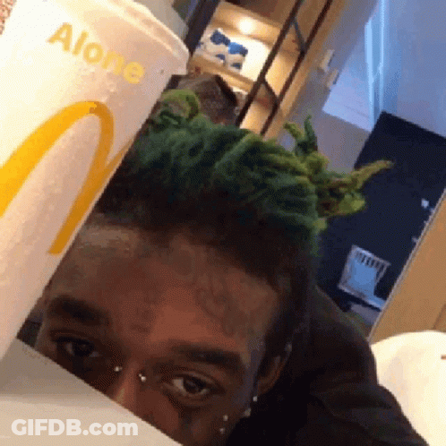 A Man With Green Hair Is Peeking Out From Behind A Mcdonalds Cup That Says Alone GIF