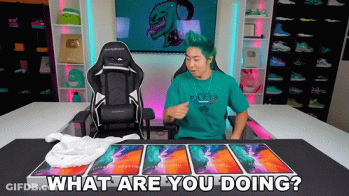 A Man With Green Hair Is Sitting In Front Of A Desk With A Chair And Says What Are You Doing GIF