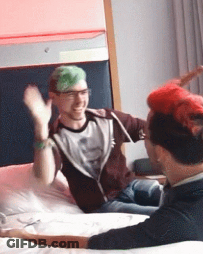 A Man With Green Hair Is Sitting On A Bed With A Man With Red Hair GIF