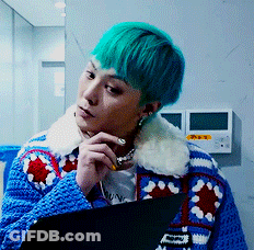 A Man With Green Hair Is Wearing A Blue Sweater With A White Collar GIF