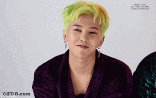 A Man With Green Hair Is Wearing A Purple Jacket And Earrings GIF