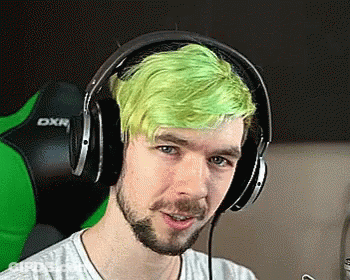 A Man With Green Hair Is Wearing Headphones And Looking At The Camera . GIF