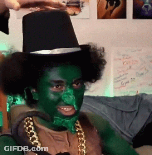 A Man With Green Paint On His Face Is Wearing A Top Hat And A Gold Chain . GIF
