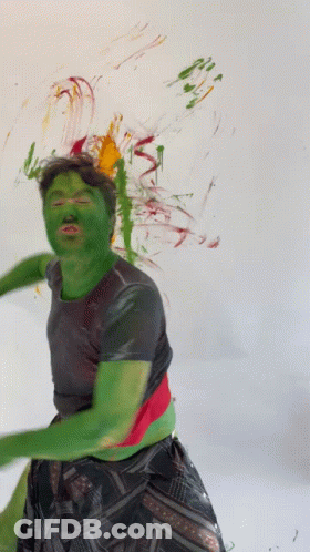 A Man With Green Paint On His Face Stands In Front Of A White Wall GIF