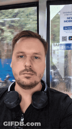 A Man With Headphones Around His Neck Stands In Front Of A Sign That Says Unlimited Data GIF