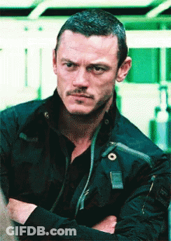 A Man With His Arms Crossed Looks At The Camera GIF