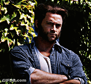 A Man With His Arms Crossed Stands In Front Of A Bush GIF