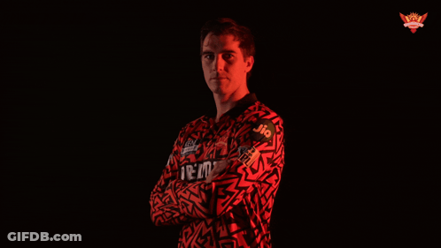 A Man With His Arms Crossed Wears A Red Shirt That Says Jio On It GIF