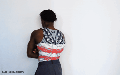 A Man With His Arms Crossed Wears A Tank Top With The Letter Gk On The Back GIF