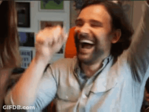 A Man With His Arms In The Air Is Laughing And Celebrating . GIF