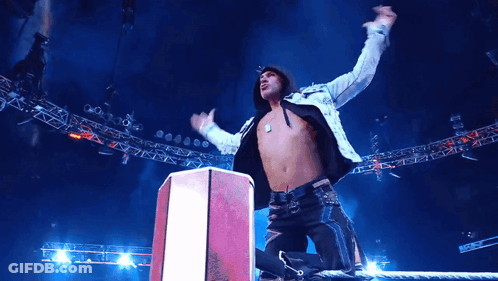 A Man With His Arms In The Air Stands On A Podium GIF