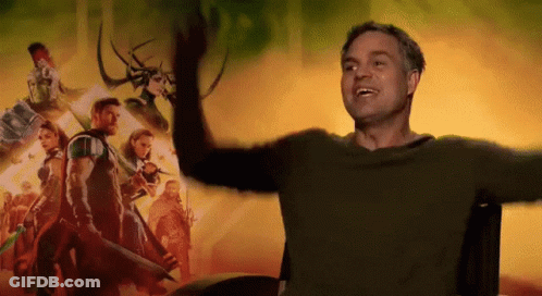 A Man With His Arms Outstretched In Front Of A Movie Poster For Thor Ragnarok GIF
