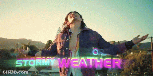 A Man With His Arms Outstretched In Front Of A Sign That Says " Stormy Weather " GIF