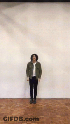 A Man With His Arms Outstretched Is Standing On A Wood Floor GIF