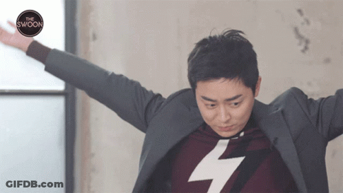 A Man With His Arms Outstretched Is Wearing A Sweater With A Lightning Bolt On It And A Suit Jacket GIF