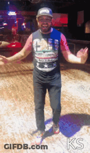 A Man With His Arms Outstretched Is Wearing A T-Shirt That Says ' Ks ' On It GIF