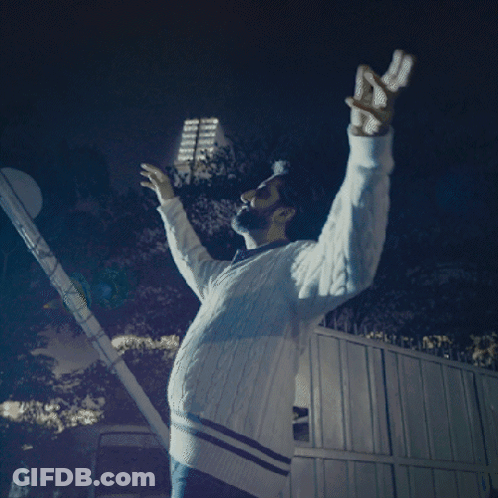 A Man With His Arms Outstretched Is Wearing A White Sweater With Blue Stripes GIF