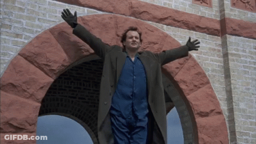 A Man With His Arms Outstretched Standing In Front Of A Brick Archway GIF