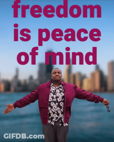 A Man With His Arms Outstretched Stands In Front Of A Sign That Says " Freedom Is Peace Of Mind " GIF