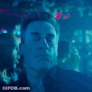 A Man With His Eyes Closed In A Dark Room With Blue Lights Behind Him GIF