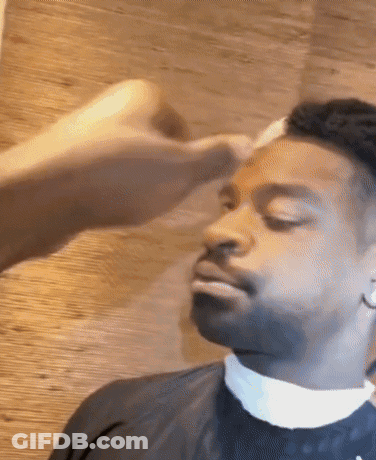 A Man With His Eyes Closed Is Getting His Hair Cut By A Barber GIF