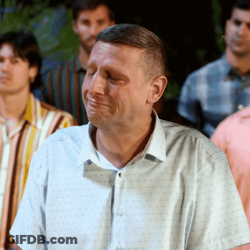 A Man With His Eyes Closed Is Standing In A Crowd Of Men GIF