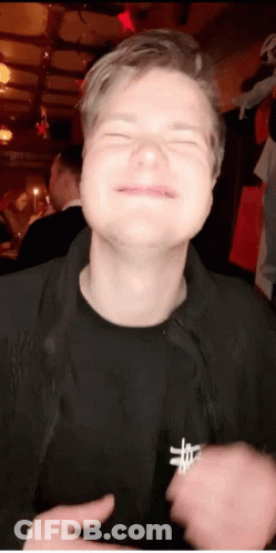 A Man With His Eyes Closed Is Wearing A Black Shirt With A Cross On The Chest GIF