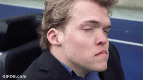 A Man With His Eyes Closed Is Wearing A Suit And A Blue Shirt GIF