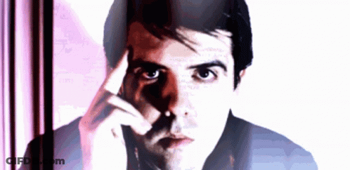 A Man With His Hand On His Forehead Looks At The Camera GIF