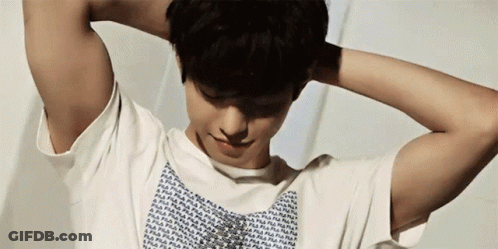 A Man With His Hands Behind His Head Is Wearing A White Fila Shirt GIF