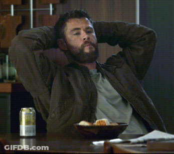A Man With His Hands Behind His Head Sits At A Table With A Can Of Beer On It GIF