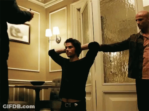 A Man With His Hands Behind His Head Stands In A Room GIF