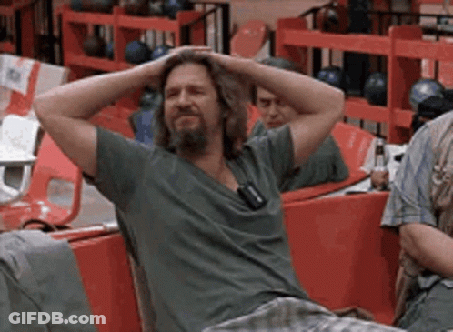 A Man With His Hands On His Head Is Sitting In A Bowling Alley GIF