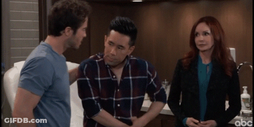 A Man With His Hands On His Stomach Is Talking To A Woman And A Man In A Blue Shirt GIF