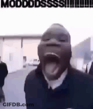 A Man With His Mouth Open And His Tongue Sticking Out Is Standing In Front Of A Building . GIF