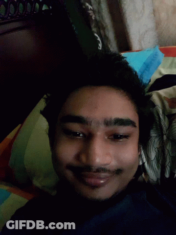 A Man With His Tongue Out Is Laying On A Bed GIF