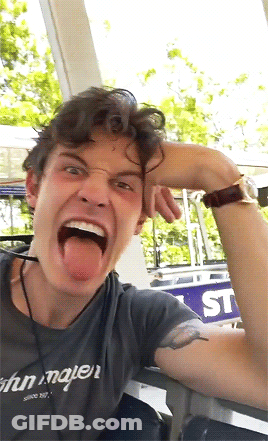 A Man With His Tongue Out Wearing A Shirt That Says John Mayer On It GIF