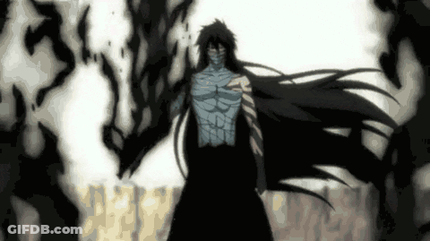 A Man With Long Black Hair And A Mask On His Face Is Standing In A Dark Room . GIF