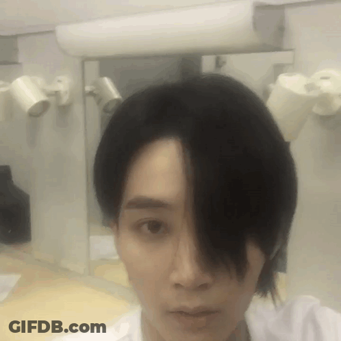 A Man With Long Black Hair Is Taking A Selfie In Front Of A Mirror GIF
