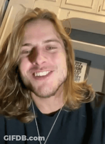 Man With Blonde Hair And Beard Smiling In Front Of Do Your Mom Sign GIF