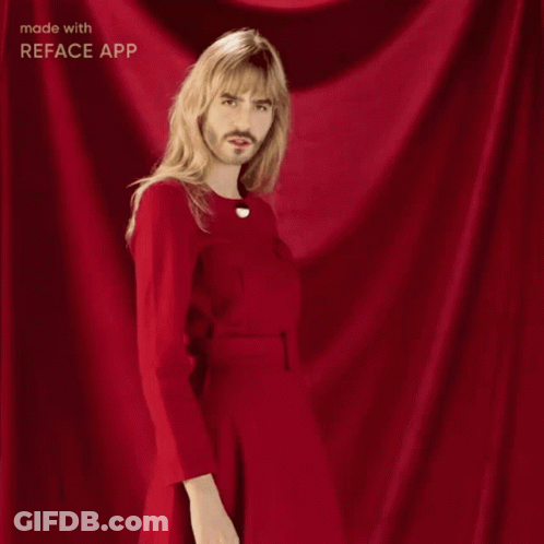 A Man With Long Blonde Hair And A Beard Is Wearing A Red Dress GIF