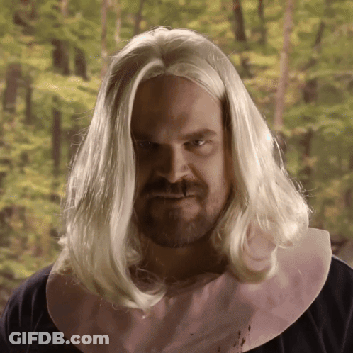 A Man With Long Blonde Hair And A Pink Bib On His Neck GIF