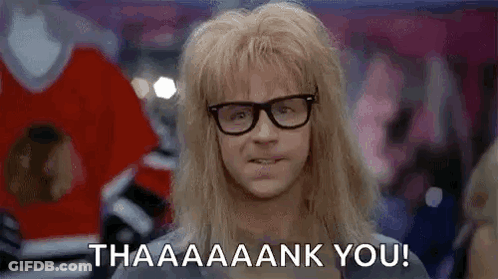 A Man With Long Blonde Hair And Glasses Is Standing In A Crowd . GIF