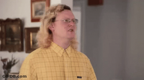 A Man With Long Blonde Hair And Glasses Is Wearing A Yellow Plaid Shirt And Glasses . GIF