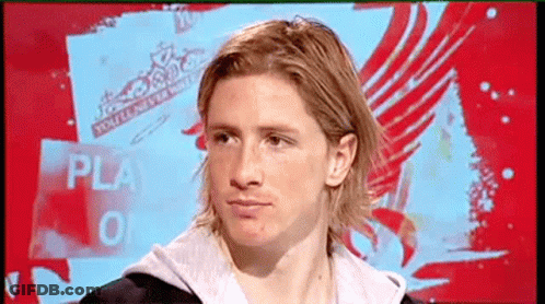 A Man With Long Blonde Hair Is Sitting In Front Of A Sign That Says Play GIF